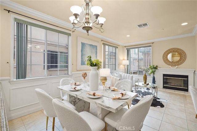 tiled dining area featuring ornamental molding and an inviting chandelier