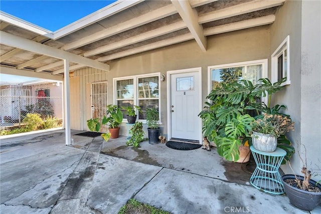 property entrance with a patio area, fence, and stucco siding