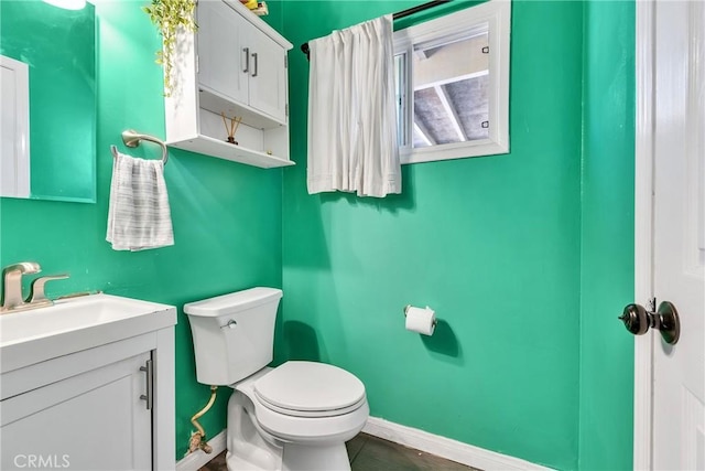 half bathroom with vanity, toilet, and baseboards