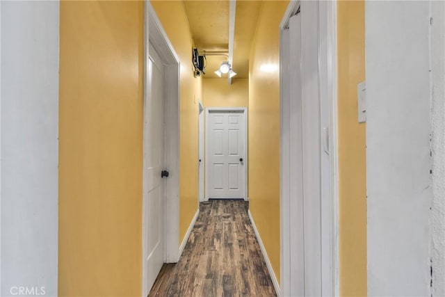 hall with dark wood-style flooring and baseboards