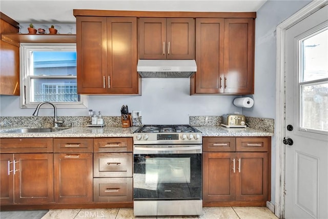 kitchen with stainless steel gas range oven, ventilation hood, a sink, and light stone countertops