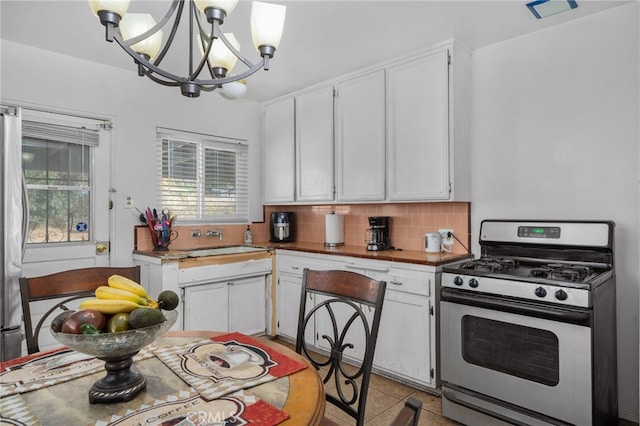 kitchen featuring white cabinets, decorative light fixtures, a chandelier, and gas range gas stove