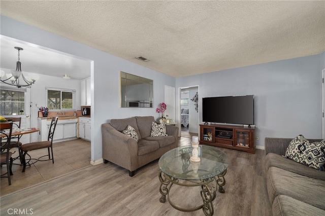 living room with a chandelier, light hardwood / wood-style flooring, and a textured ceiling