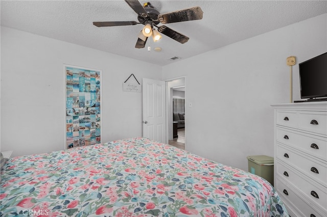 bedroom with ceiling fan and a textured ceiling