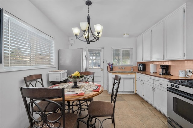 kitchen with backsplash, stainless steel appliances, an inviting chandelier, white cabinets, and hanging light fixtures