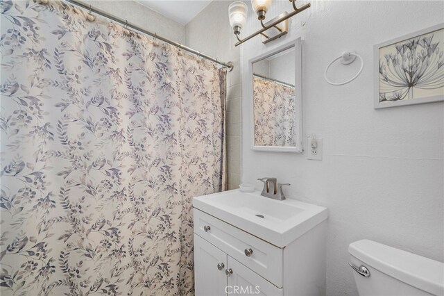 bathroom featuring walk in shower, vanity, a notable chandelier, and toilet