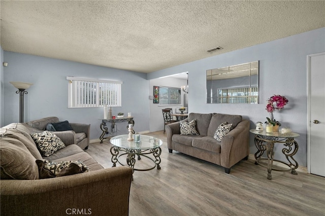 living room featuring a chandelier, hardwood / wood-style floors, a textured ceiling, and a wealth of natural light