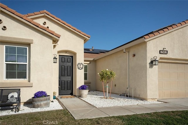 entrance to property featuring a garage and solar panels