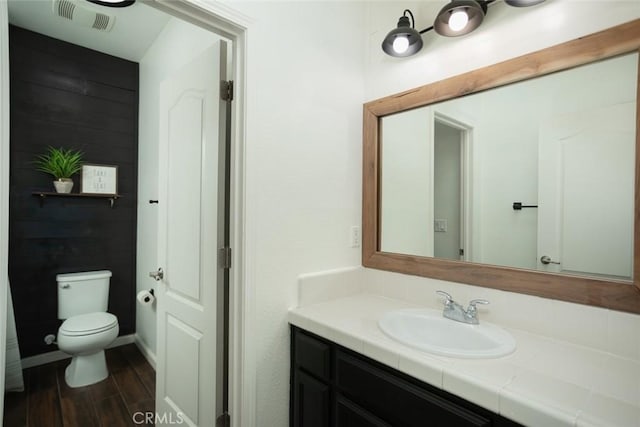 bathroom with toilet, vanity, and wood-type flooring