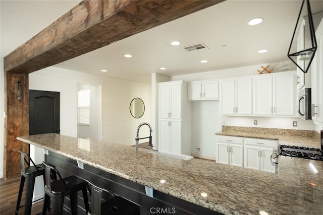 kitchen featuring appliances with stainless steel finishes, white cabinetry, a breakfast bar, and sink