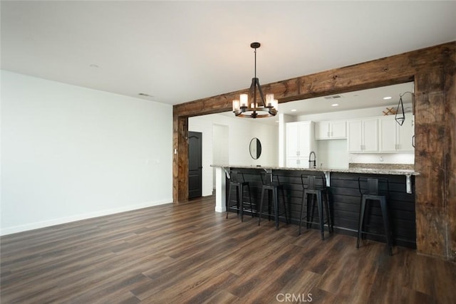 kitchen featuring decorative light fixtures, dark hardwood / wood-style flooring, light stone counters, and white cabinetry