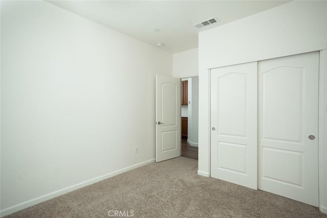 unfurnished bedroom with light colored carpet and a closet