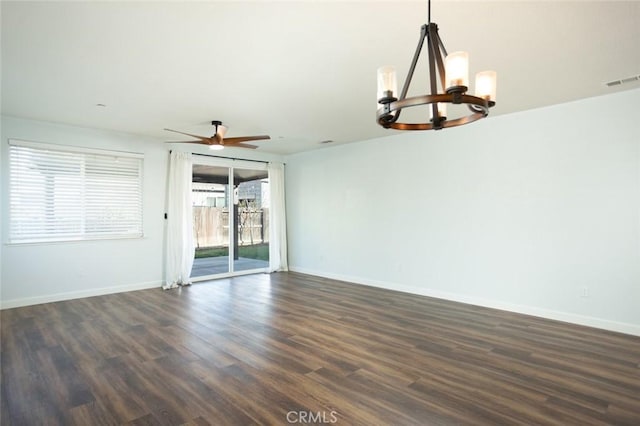 spare room featuring ceiling fan with notable chandelier and dark wood-type flooring