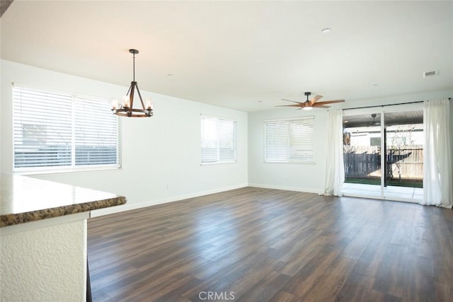 empty room featuring dark wood-type flooring and ceiling fan with notable chandelier