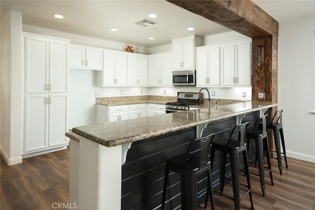 kitchen with kitchen peninsula, white cabinetry, and stainless steel appliances