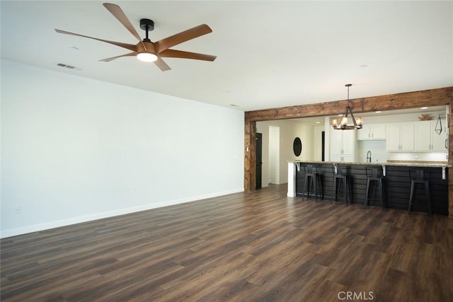 unfurnished living room with dark hardwood / wood-style flooring, ceiling fan with notable chandelier, and sink