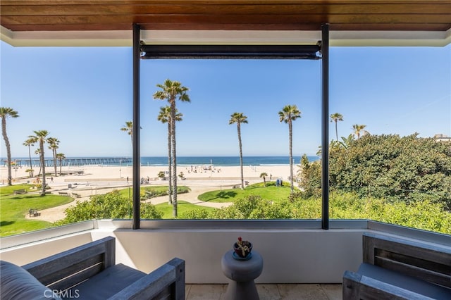 view of patio / terrace featuring a water view, a balcony, and a beach view