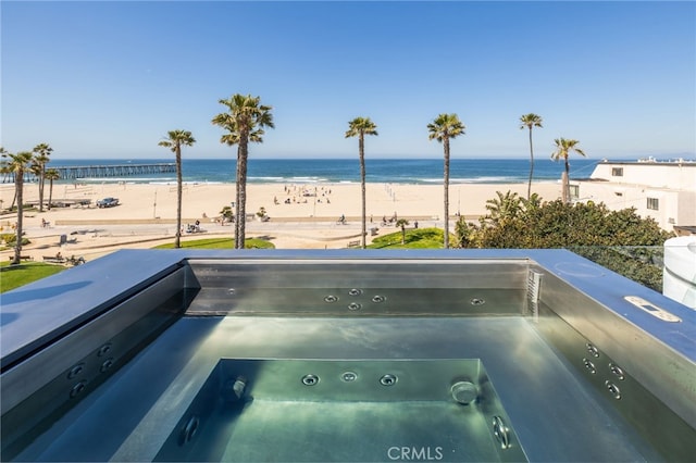 exterior space featuring a beach view, a water view, and a hot tub