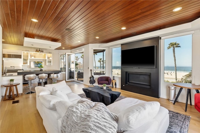 living area featuring light wood-type flooring, a fireplace, wood ceiling, and recessed lighting