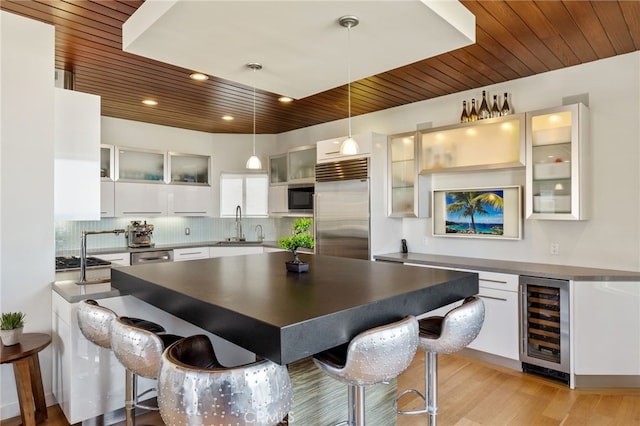 kitchen featuring stainless steel appliances, backsplash, wood ceiling, and beverage cooler