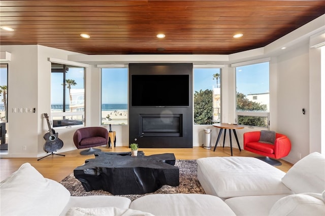 living room featuring a glass covered fireplace, wood ceiling, wood finished floors, and recessed lighting