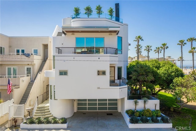 back of house featuring stucco siding, an attached garage, and stairway