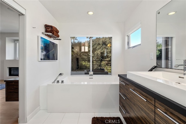 full bath featuring vanity, a bath, recessed lighting, and baseboards