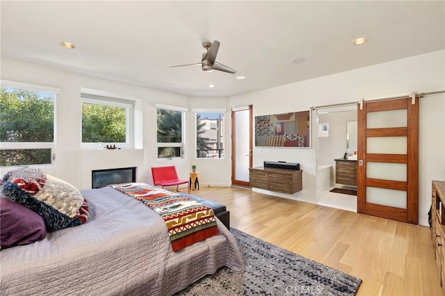 bedroom with recessed lighting, light wood-style floors, a glass covered fireplace, and a ceiling fan