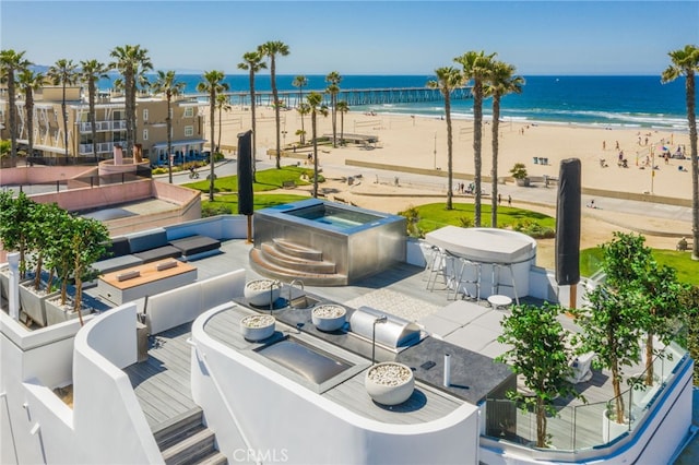 view of patio / terrace with a view of the beach, a jacuzzi, and a water view