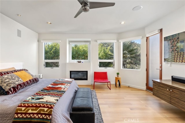 bedroom featuring visible vents, recessed lighting, light wood-style floors, and a glass covered fireplace