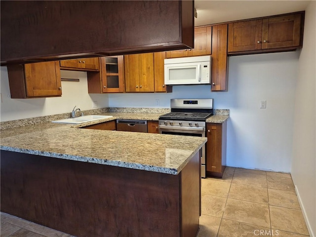 kitchen featuring sink, light tile patterned floors, light stone counters, kitchen peninsula, and stainless steel appliances