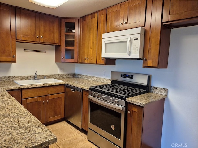 kitchen featuring light stone counters, sink, light tile patterned flooring, and stainless steel appliances