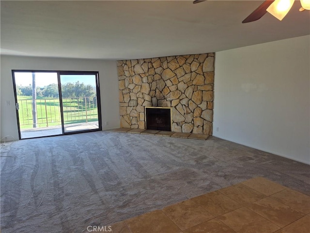 unfurnished living room with carpet, ceiling fan, and a stone fireplace