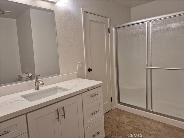 bathroom with tile patterned flooring, vanity, toilet, and an enclosed shower