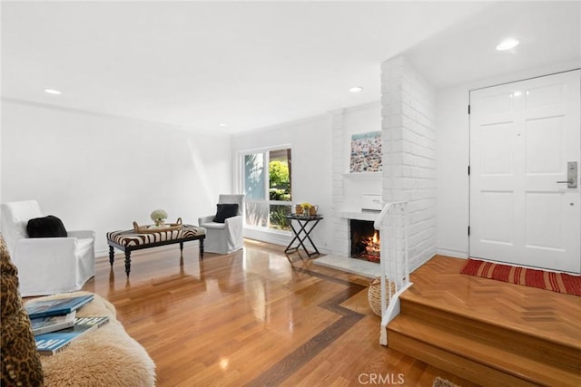 interior space featuring wood-type flooring, a brick fireplace, and crown molding