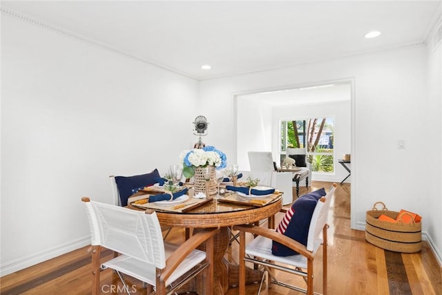 dining space with wood-type flooring and crown molding