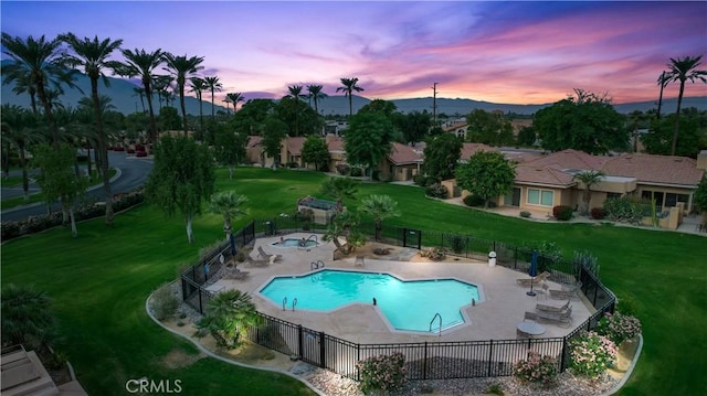 pool at dusk featuring a lawn and a patio area