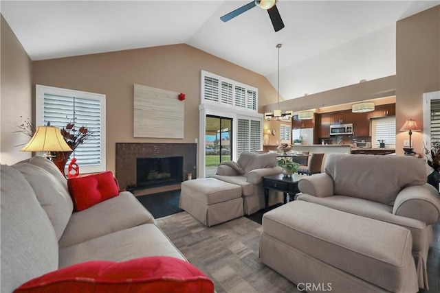 living room featuring ceiling fan, a tile fireplace, and lofted ceiling