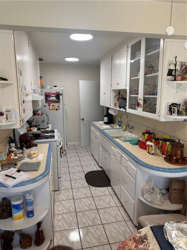 kitchen featuring tile counters, white cabinets, white appliances, and sink