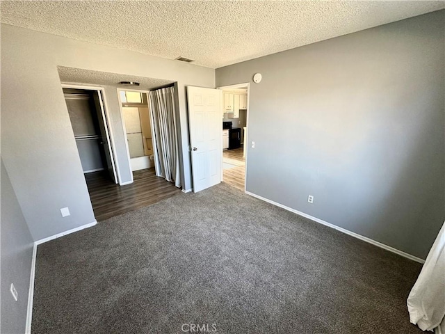 unfurnished bedroom with a closet, a textured ceiling, and dark colored carpet