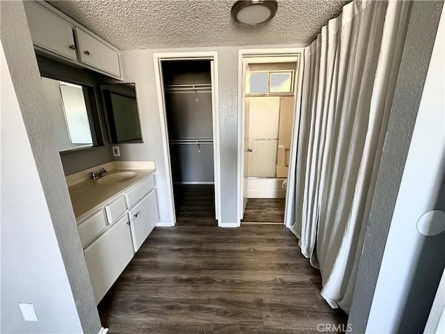 bathroom featuring hardwood / wood-style flooring, vanity, shower / bath combination with curtain, and a textured ceiling