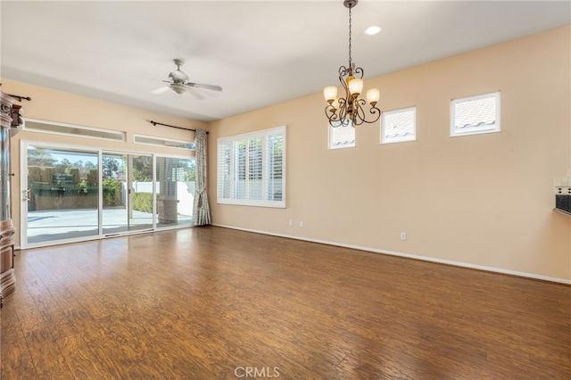 spare room featuring ceiling fan with notable chandelier and dark wood-type flooring