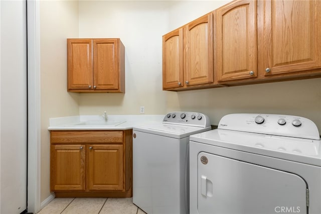 clothes washing area with cabinets, separate washer and dryer, light tile patterned flooring, and sink