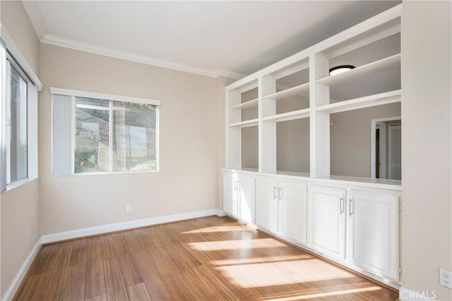 empty room with light wood-type flooring and ornamental molding