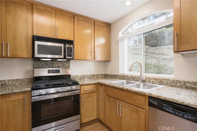 kitchen with a wealth of natural light, sink, stainless steel appliances, and light stone counters