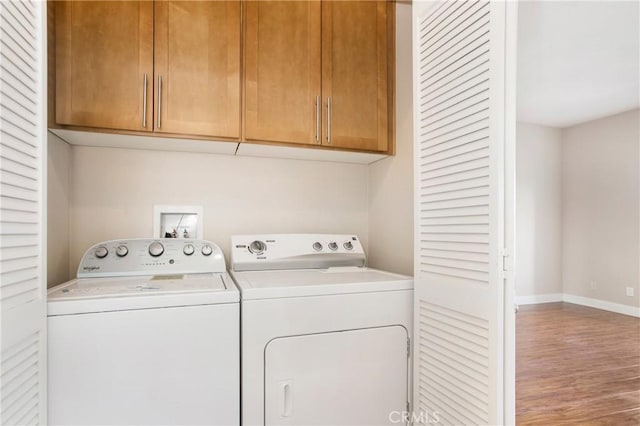 clothes washing area featuring hardwood / wood-style floors, cabinets, and independent washer and dryer