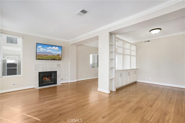 unfurnished living room with a fireplace, light hardwood / wood-style flooring, built in features, and crown molding