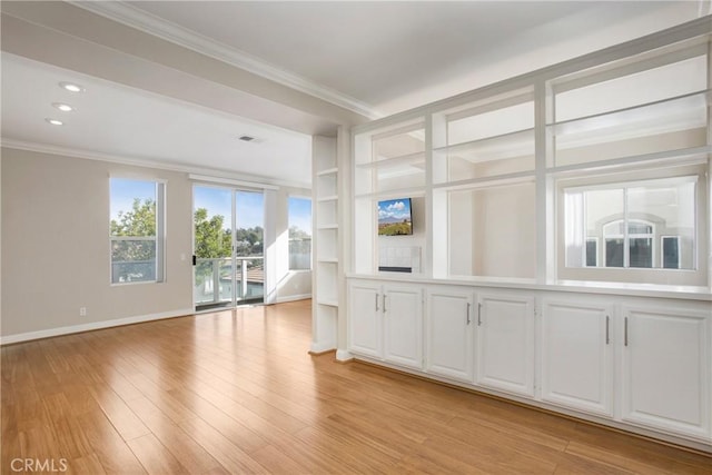 unfurnished living room with light wood-type flooring, built in features, and ornamental molding