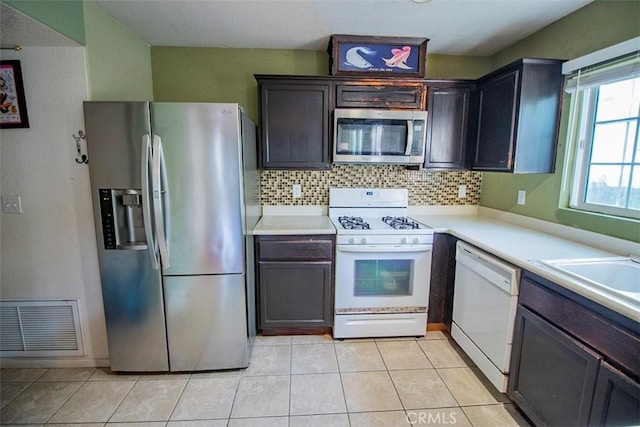 kitchen featuring light tile patterned flooring, dark brown cabinetry, backsplash, and appliances with stainless steel finishes