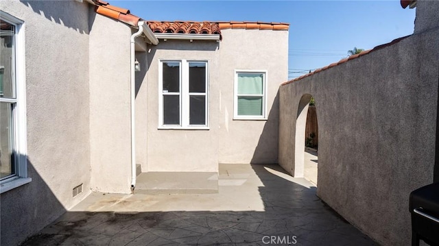 exterior space with a tiled roof, a patio, fence, and stucco siding